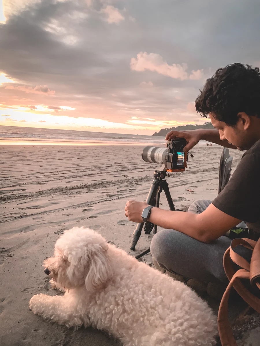 Azar photographing a beach sunset with his dog, Quepos, Puntarenas