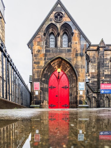 Red church door reflected in rainwater, Edinburgh, Scotland